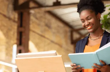 A smiling woman holds a book, radiating joy and enthusiasm for reading.